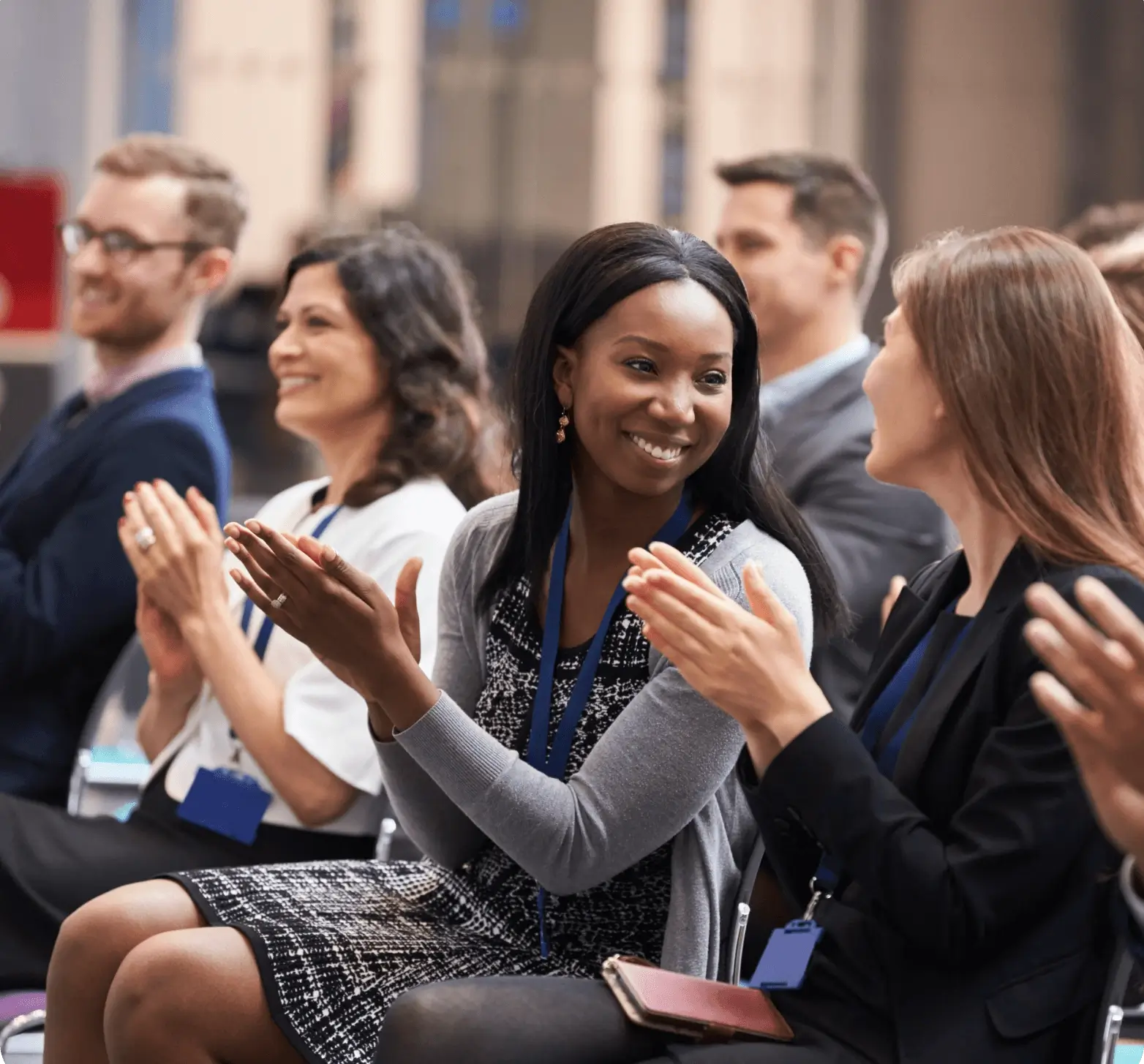 Audience members clapping and smiling during a presentation.