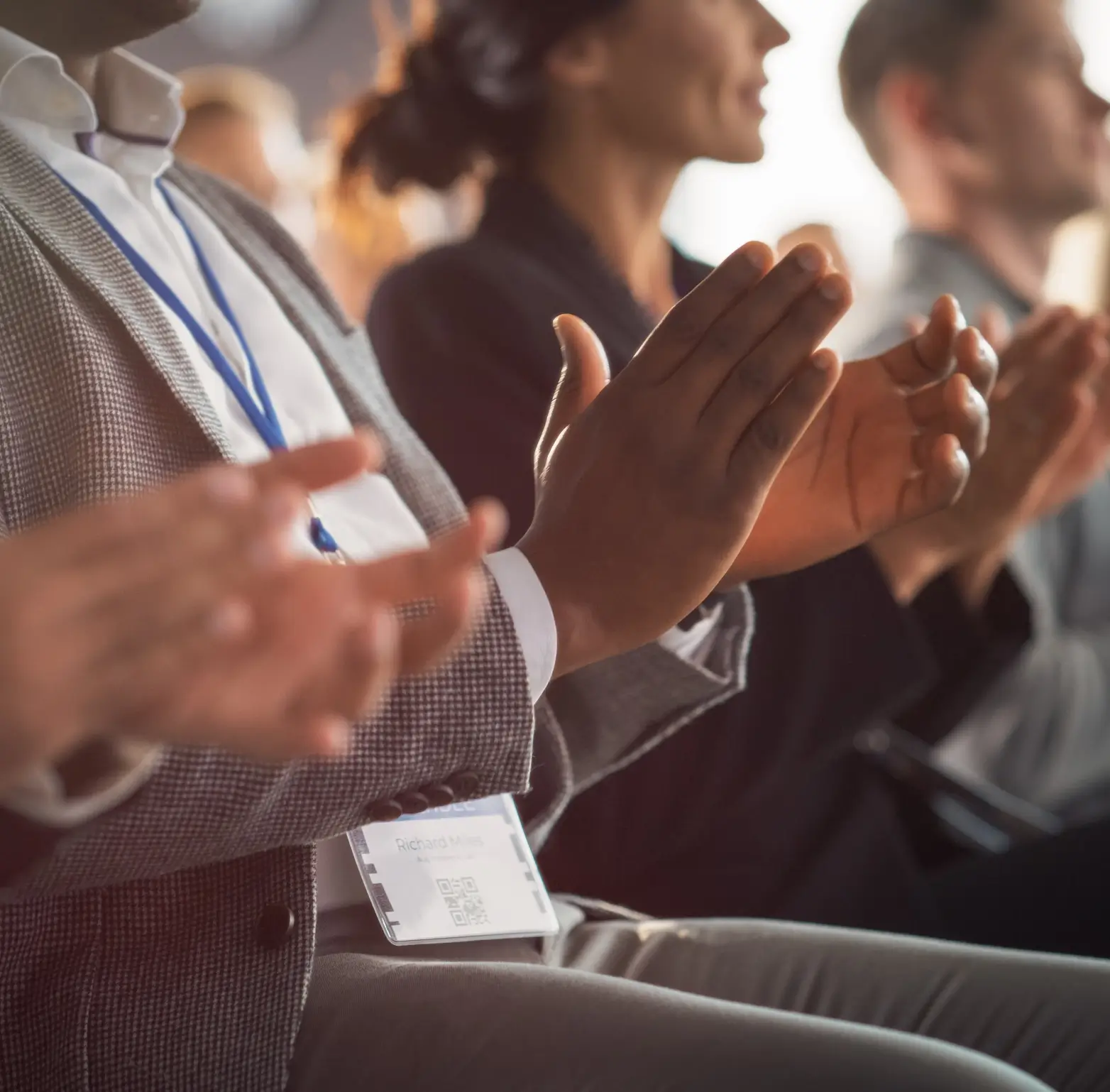 Close-up of people clapping at an event.