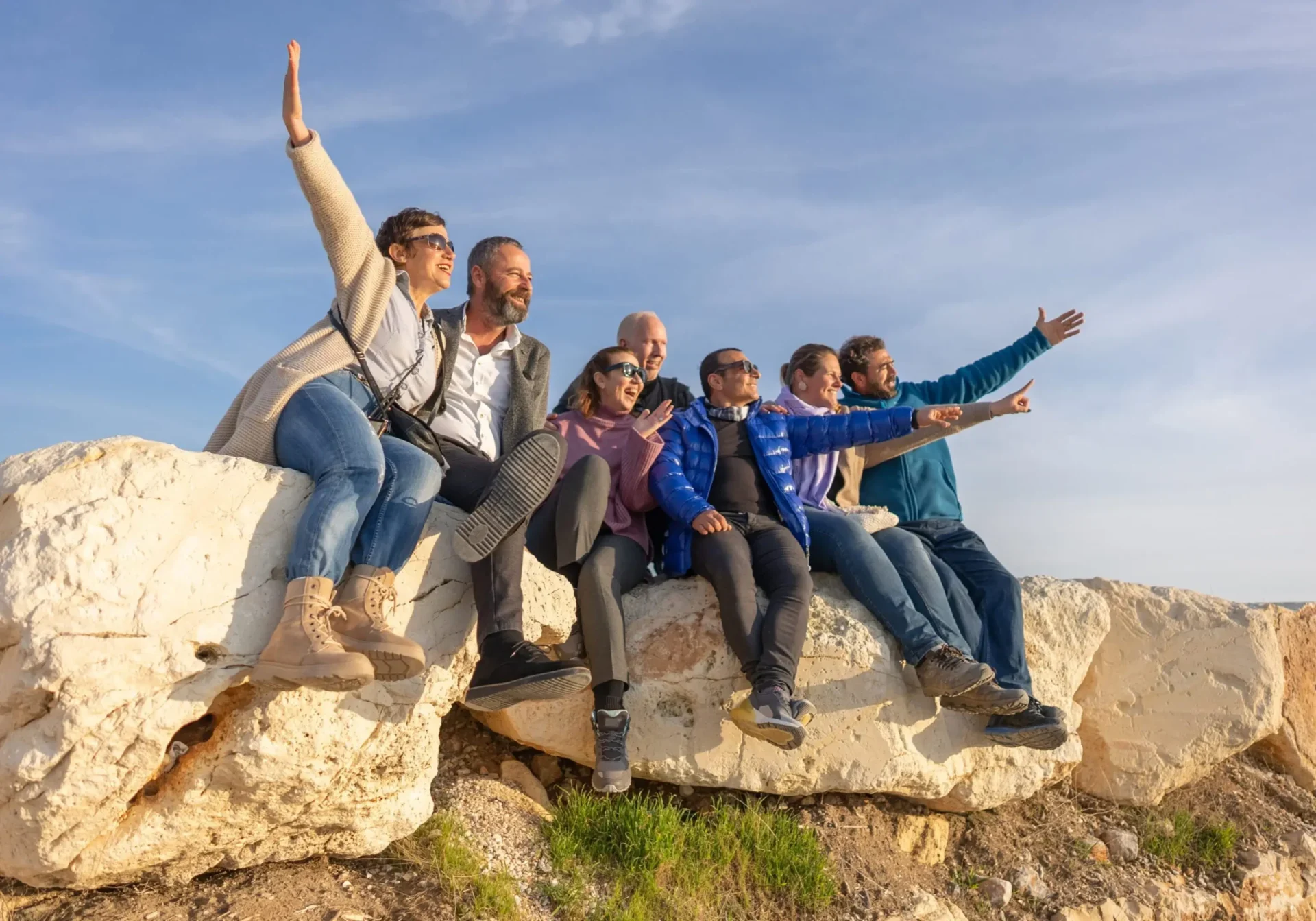 Group of friends sitting on large rocks, enjoying a sunny day outdoors.