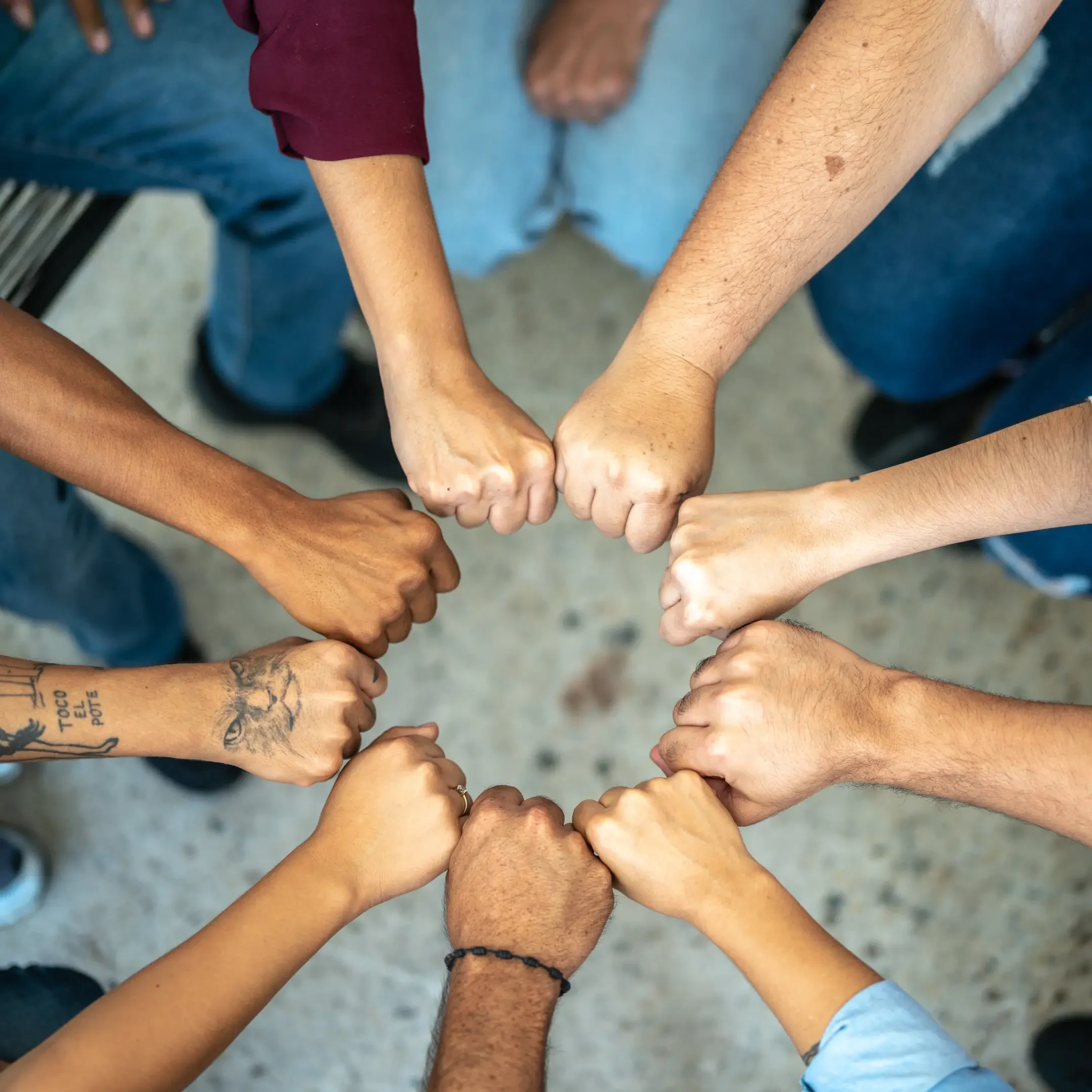 Diverse group joining fists in unity circle.